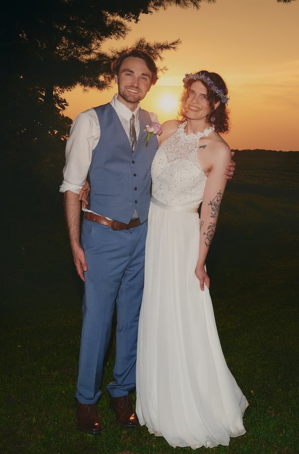 a bride and a groom standing in front of a sunset
