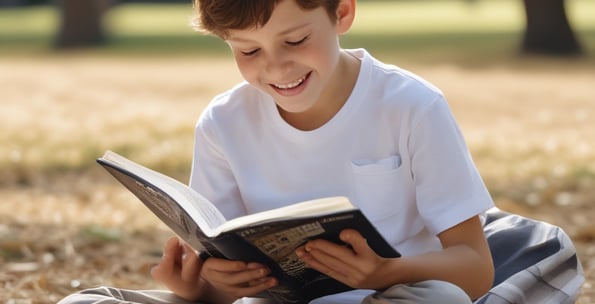 a boy is sitting on the ground and reading a book