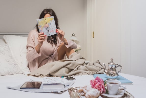 a woman sitting on a bed with a book and a cup of coffee