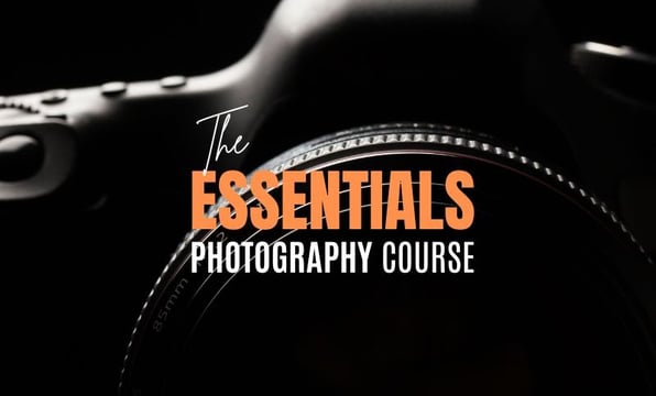 Close-up of a camera lens with text “The Essentials Photography Course” overlayed.