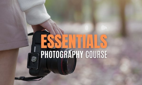 Close-up of a person holding a DSLR camera with text overlay reading Essentials Photography Course.