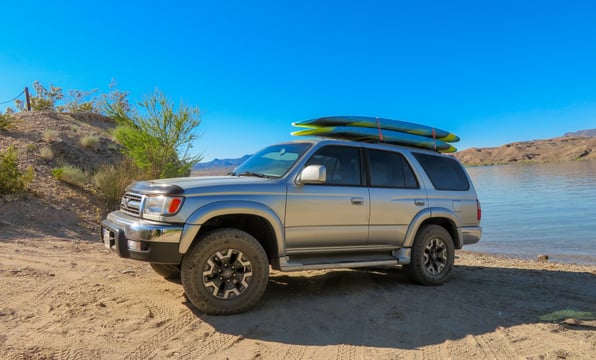4runner with paddle boards on top next to the river