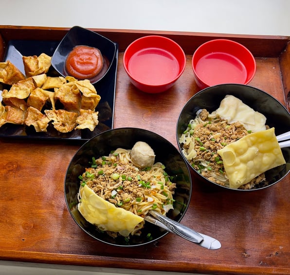 Tray berisi dua mangkuk mie ayam dengan topping lengkap, dua mangkuk saus, dan pangsit goreng
