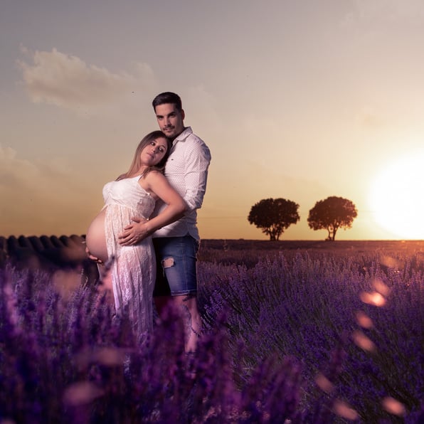 campos de lavanda con preciosa puesta de sol , futura mama y papa esperando a su bebe  en gesto cariñoso 