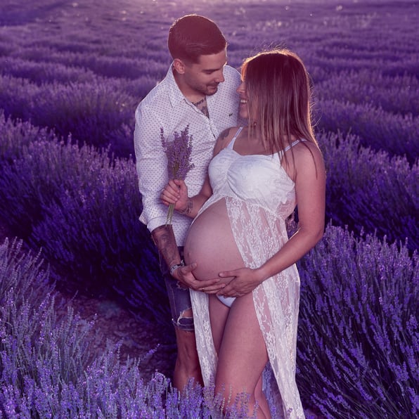 futuros papas mirandose con ternura  en  exterior y campos de lavanda, con ramo de flores en mano  