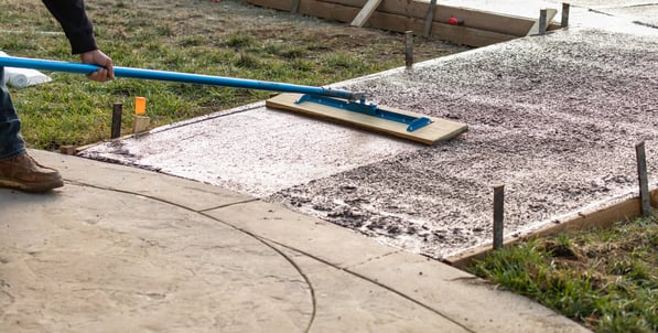 a person using a broom to clean a sidewalk