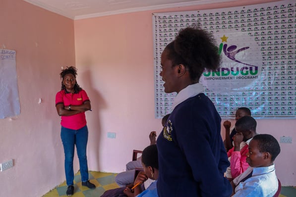 a woman standing in front of a classroom with a group of children