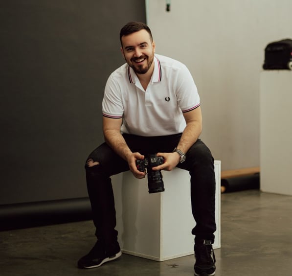 a man sitting on a white cube with a camera
