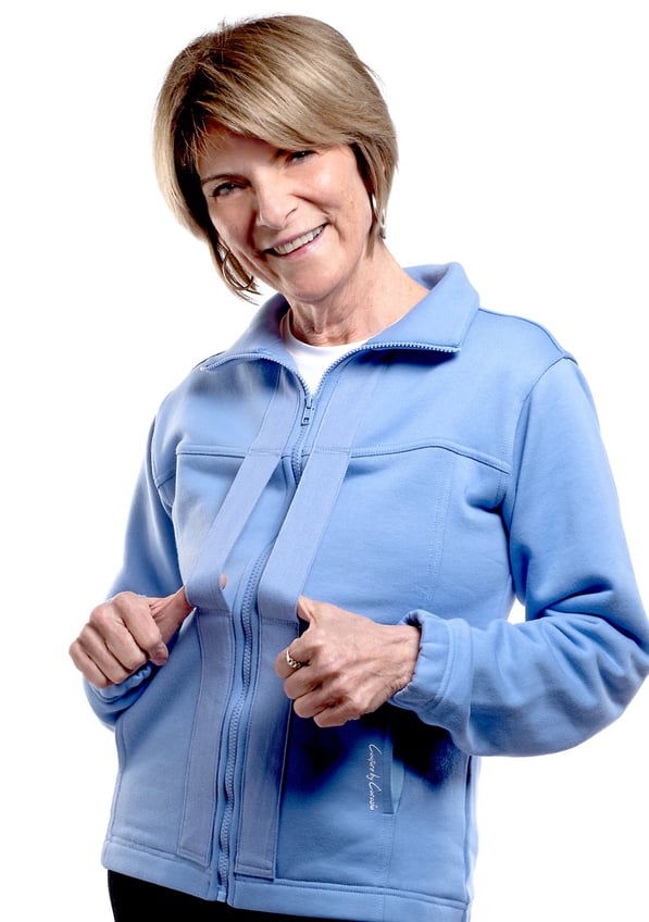 Smiling blonde model wearing blue Easeability Jacket with thumbs in front handles