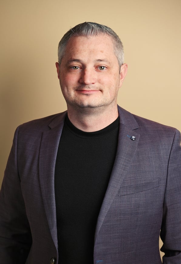 a man in a suit and black shirt with indoor lighting