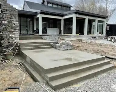 a house with a large concrete patio with steps leading up to a large house