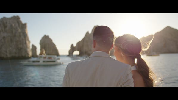 A couple of lovers watching the iconic Cabo San Lucas arch from a boat, with golden light