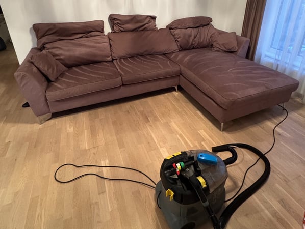 sofa su šalia stovinčia gilaus valymo chemijos mašina karcher, demonstruojanti švarią sofą