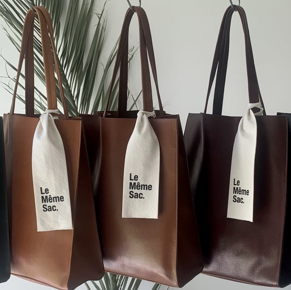 Bolsos Tote colgados en fila con degradé de colores, destacando la belleza del cuero y la elegancia 