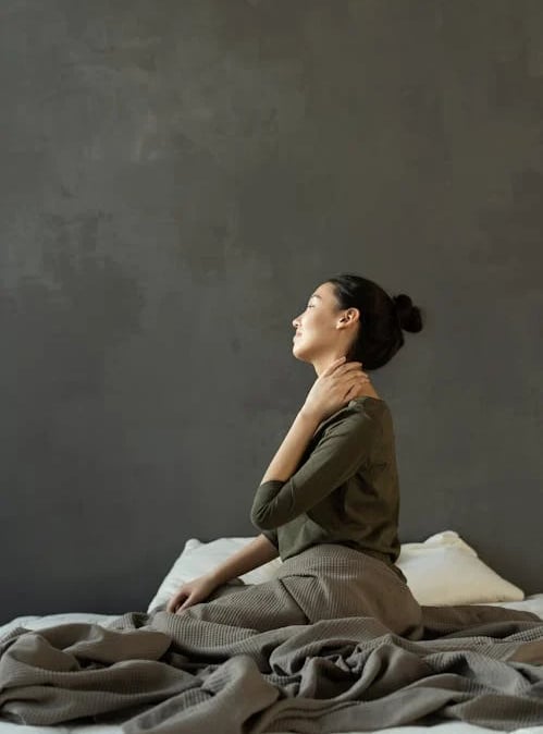 a woman sitting on a bed with a blanket on it