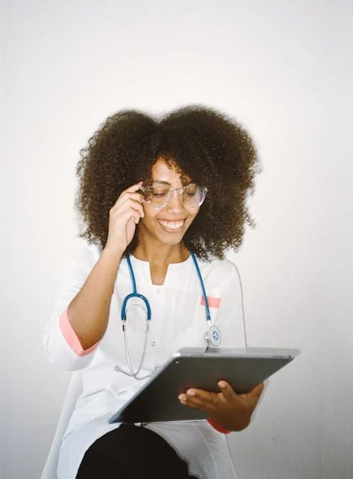 a woman in a white lab coat and glasses talking on a cell phone