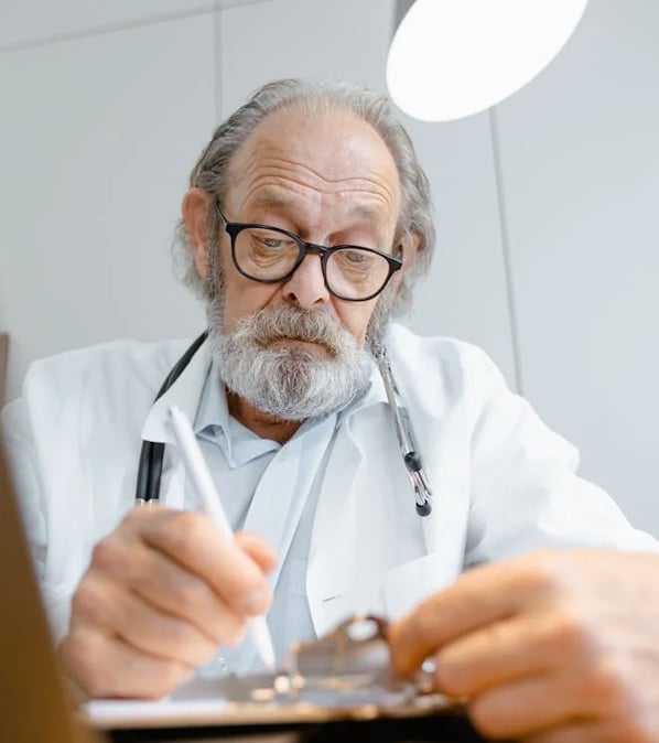 a man in a lab coat and glasses is looking at a clipboard