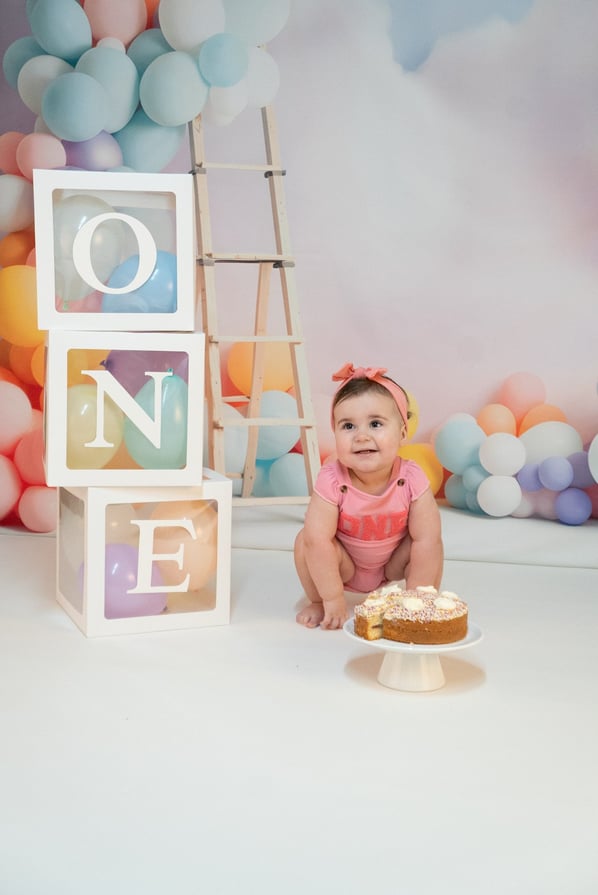 a baby girl sitting on a cake with a cake