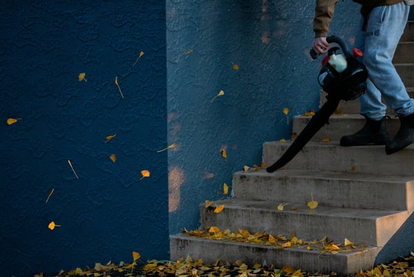 a man on stairs with leafblower removing debris