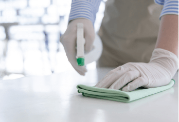 une personne portant des gants et nettoyant une table