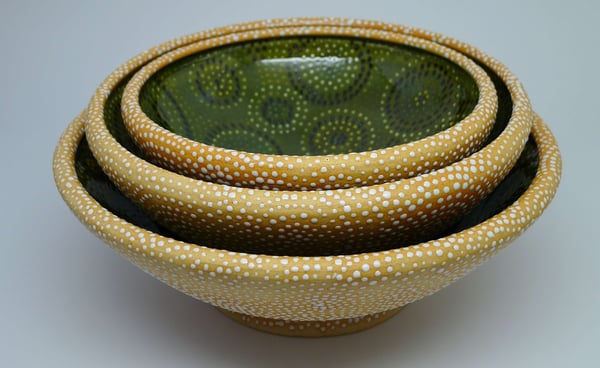 Set of large nesting bowls with rolled rims, glazed on inside, dotted on outside