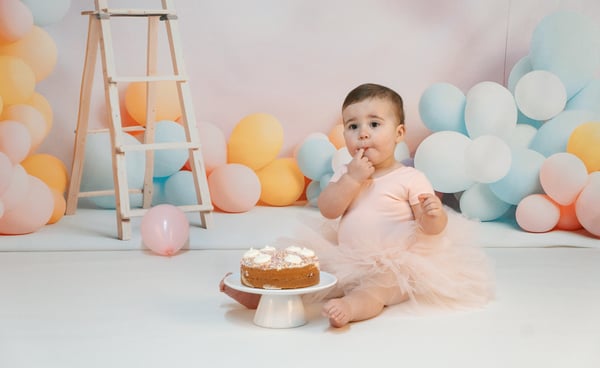 a baby girl in a pink tutu and a cake