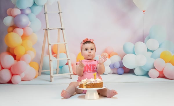 a baby girl sitting on a cake with a cake