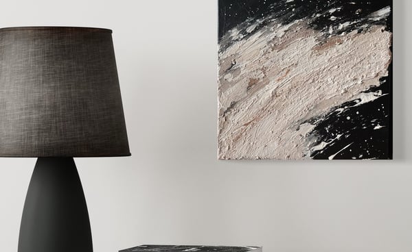 a lamp on a table with books and a abstract painting with natural colors