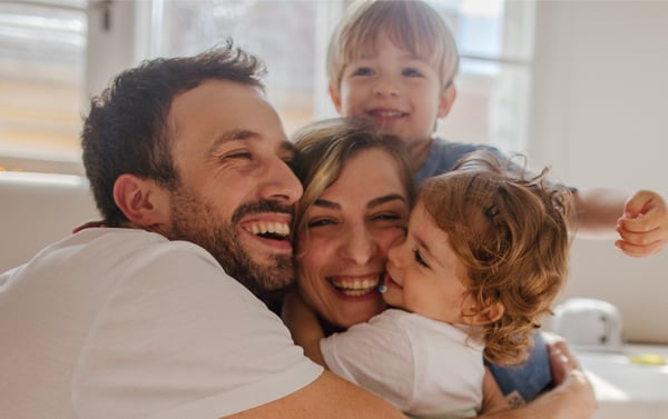 família feliz com um casal e duas crianças protegidas e felizes - seguro de vida, proteção, abraço