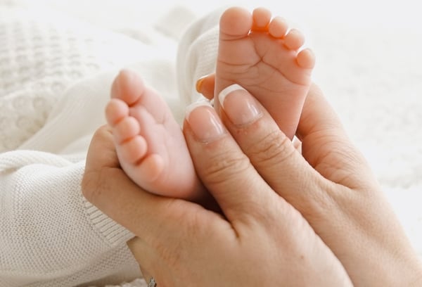 a woman holding a baby's feet up to her feet