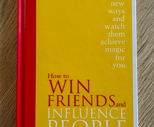 yellow book on wooden table, Dale Carnegie, how to win friends and influence people