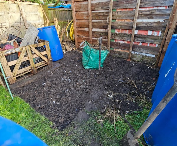 a garden with a wooden fence and a blue plastic bag