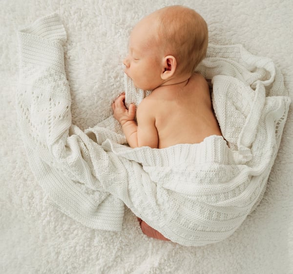 a newborn baby is sleeping in a blanket - Lincolnshire photography studio