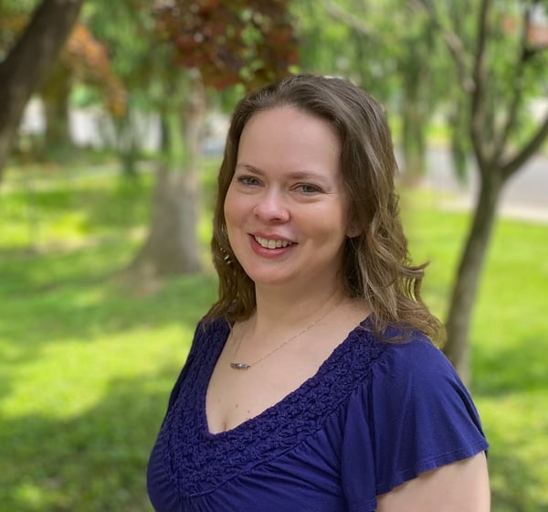 Happy woman facing forward with trees behind her