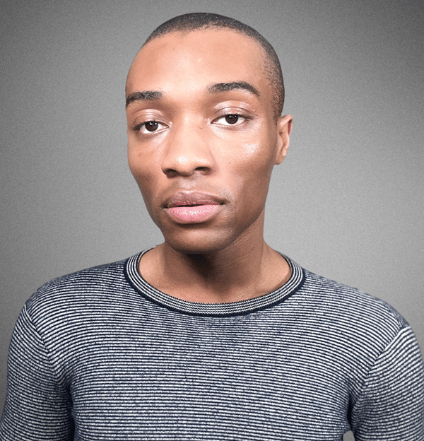 a man with a horizontally striped navy blue and white shirt, standing against a grey background