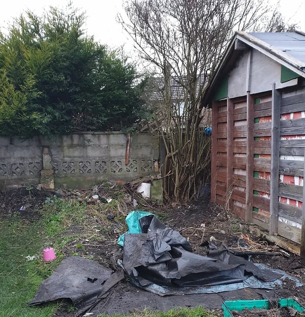 a shed with a pile of garbage and trash bags