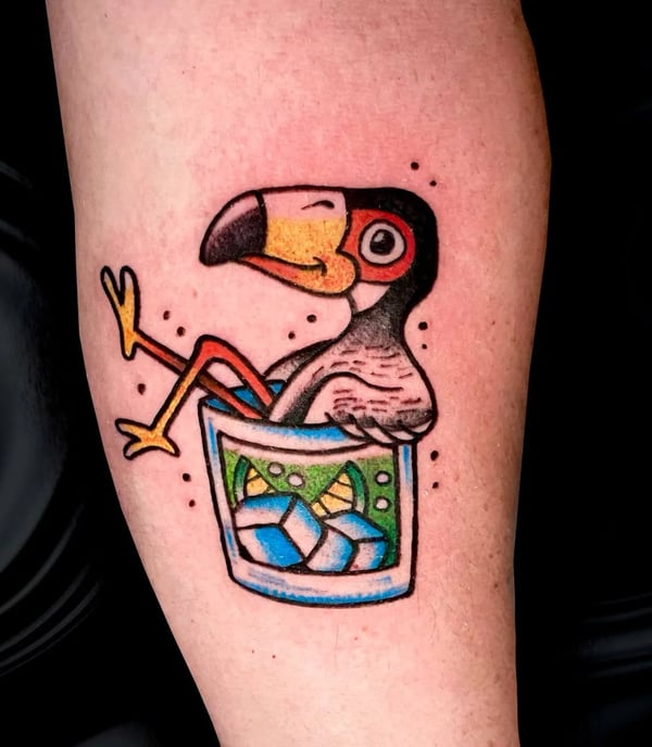 a cartoonish tattoo of a toucan taking a bath in a glass of some drink
