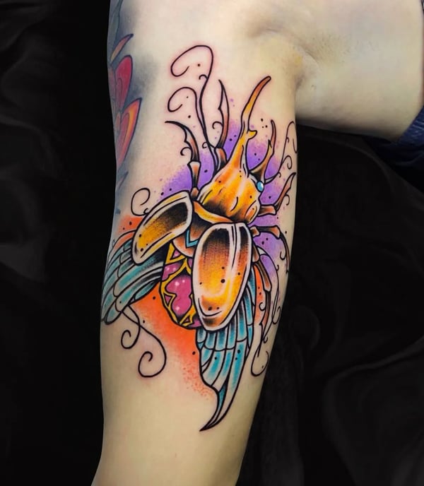 a neaotraditional tatto about an egiptian scrab made with gold and gems