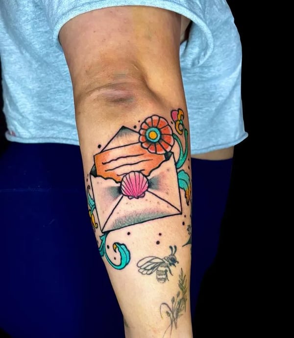 Traditional american tattoo of a love letter with a seashell and flowers