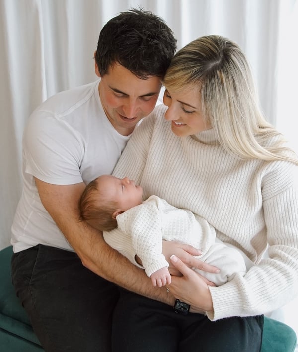 a man and woman holding a baby in a living room