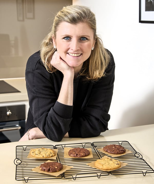 Olivia, Chief Cookie Officer, smiles with a tray of freshly baked cookies in front of her.