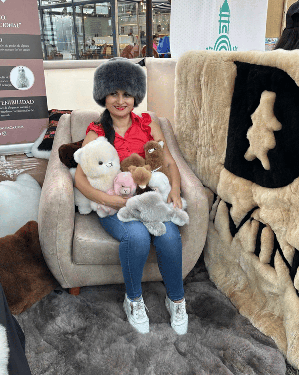 A woman sitting in a chair with alpaca plushies at the APAVIT International Tourism Fair