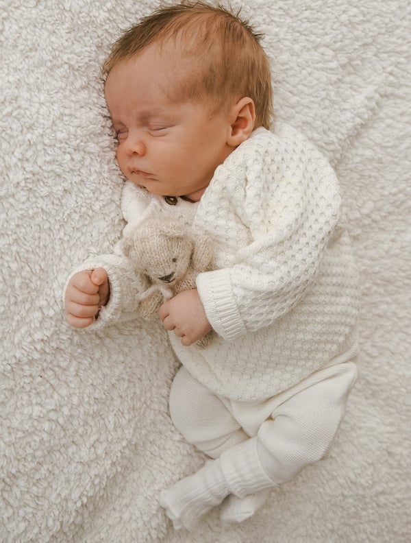 a baby is sleeping on a blanket and holding a teddy bear