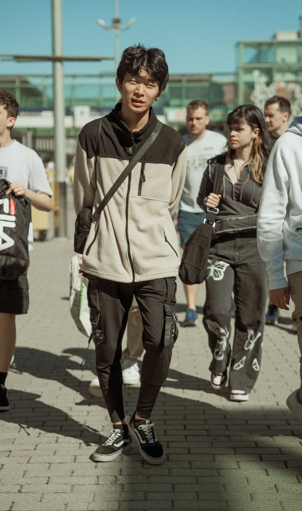 Young man in a two-tone fleece jacket and cargo pants at Japan Weekend IFEMA in Bilbao. Casual streetwear style at the event