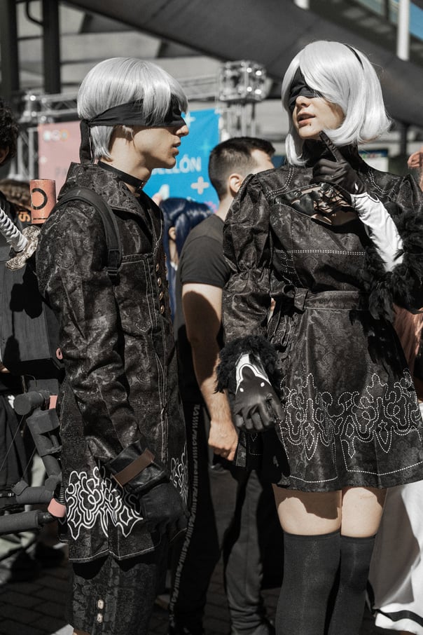 Two cosplayers dressed as 2B and 9S from Nier: Automata at an event in Bilbao, Spain. Detailed black costumes and blindfolds.