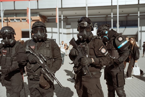 Group of cosplayers in black tactical outfits with gas masks and prop firearms at an event in Bilbao, Spain. Military or sci-