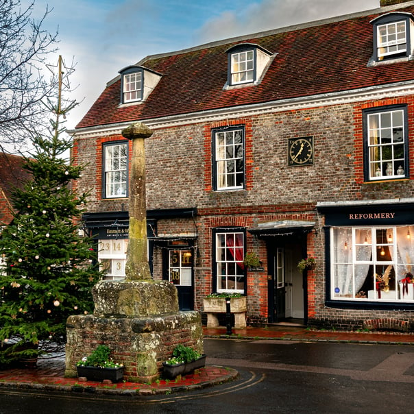 A shot of an old building in Alfriston, in front of it is the village christmas tree and a stone memorial statue