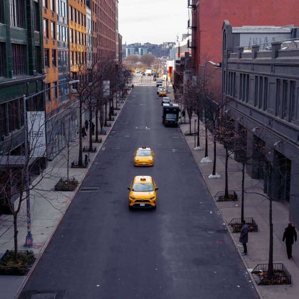 two yellow taxis drive down the centre of an empty new york city street