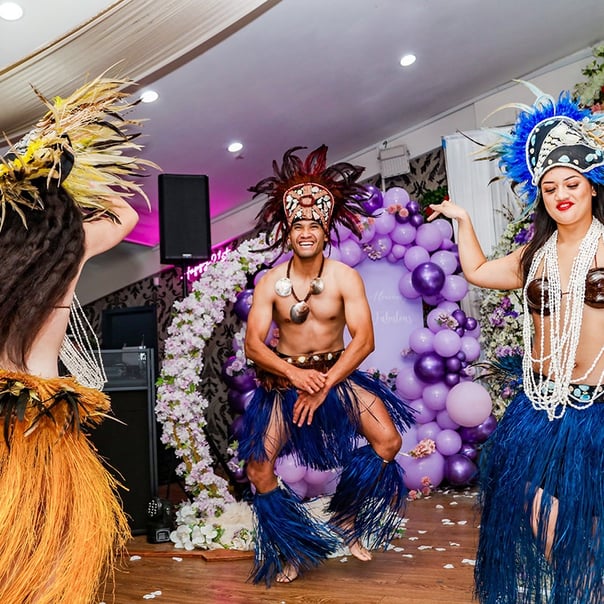 Two women and a man dressed in traditional Maori clothing perform a dance, showcasing their culture and traditions.