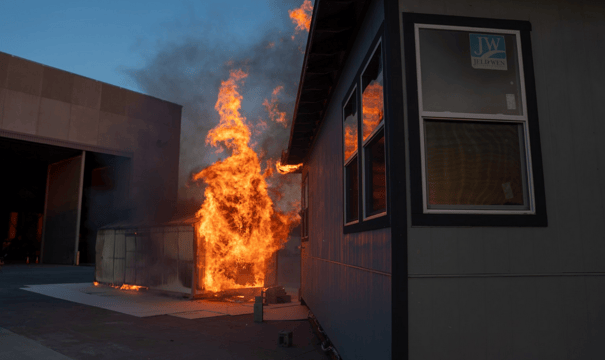 IBHS research center testing fire prevention for properties showing an engulfed structure next to another building catch fire